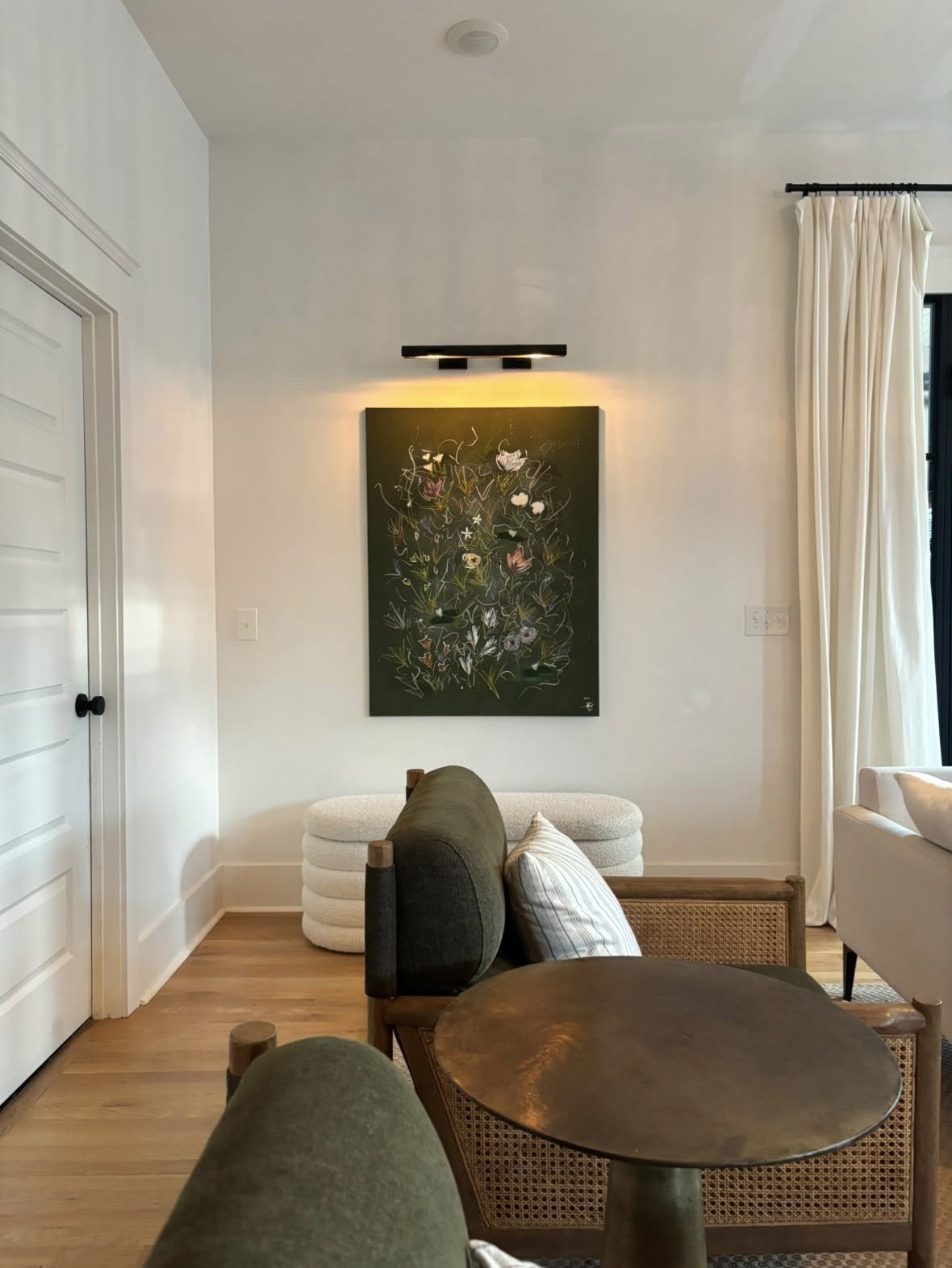 A deep green floral canvas hung above a boucle bench in a client's sitting room